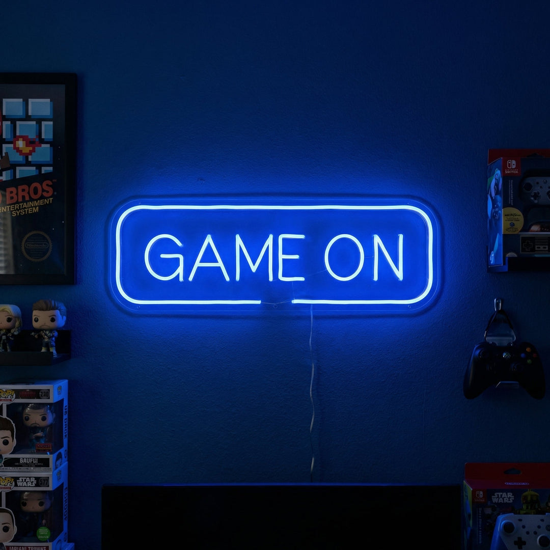 Blauw neon LED “GAME ON” boven dual-monitor setup, decoratie voor gaming room.