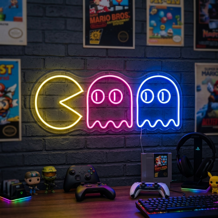 Geel Pac-Man neon LED-bord met twee kleurrijke spoken, retro decoratie op bakstenen muur.