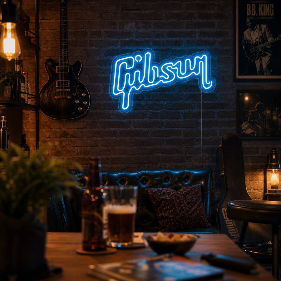 Blauw neon LED-bord met Gibson-logo, wanddecoratie voor muziekstudio of oefenruimte.