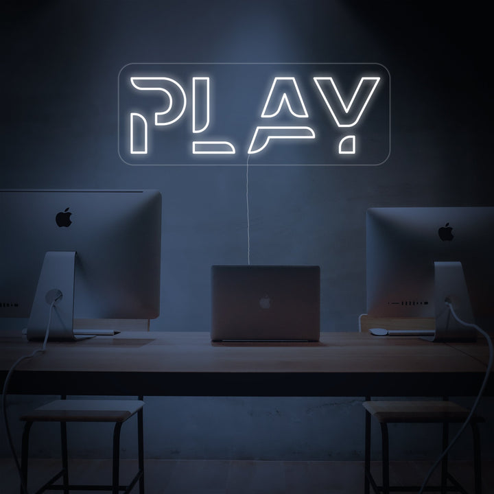 Wit neon LED-bord “PLAY” boven pc-setup, moderne verlichting voor gamingruimte.